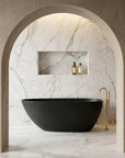 Modern bathroom with the Bellastone ARIA 1700mm freestanding bathtub in black, marble walls, and gold fixtures.