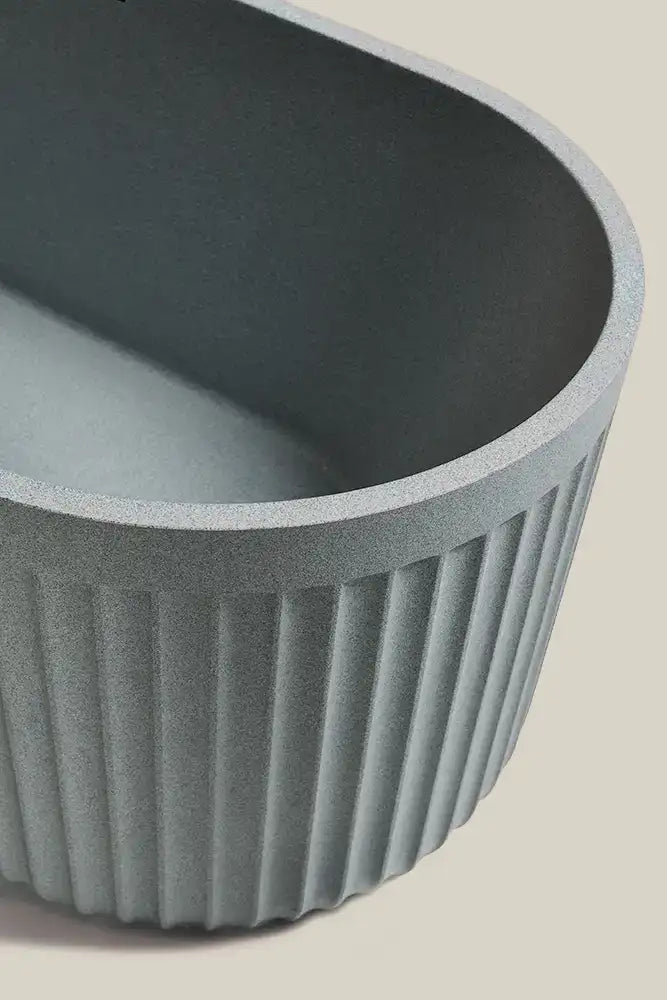 Close up of a Bellastone DORIA freestanding bath in granite grey on a beige background