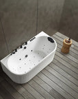 A top view of the Bellastone Doria back-to-wall with faucet bathtub in white with black tap ware, in a modern bathroom with wooden floor and gray walls.